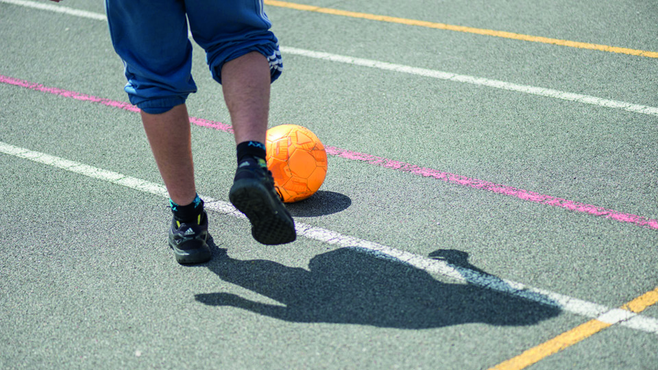 child playing football on concrete