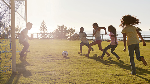 Children playing football in the sun