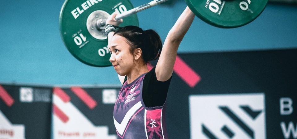 female athlete holding weights in competitive gym setting