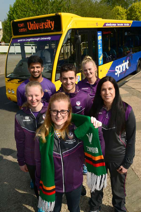 students standing in front of a Kinch bus