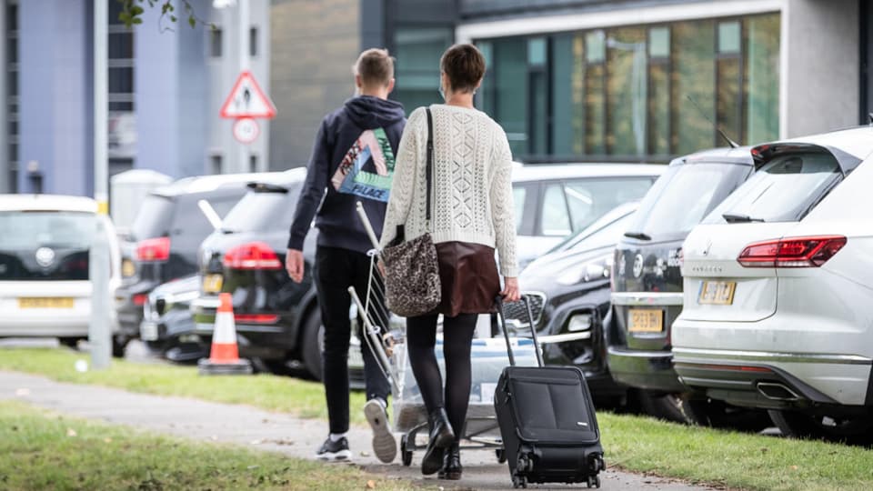 a mother and son arriving to their hall with a suitcase