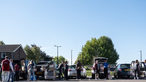cars parked up in a row with parents, students and fresher helpers unpacking