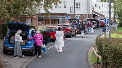 cars parked up in a row with parents, students and fresher helpers unpacking