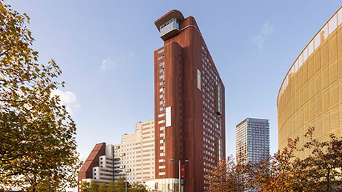 External view of Stratford One Loughborough London student accommodation. The building is tall, modern and stylish, giving incredible views of the city from the roof garden terraces and sky lounge visible at the top of the building. The building is a rich clay red colour.
