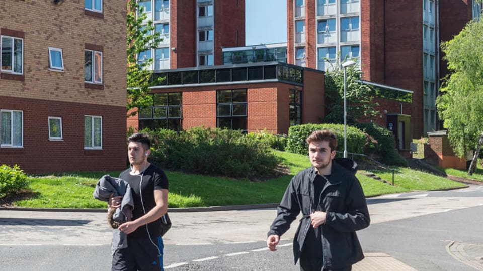 Two male students walk outside of Loughborough University's David Collett hall.