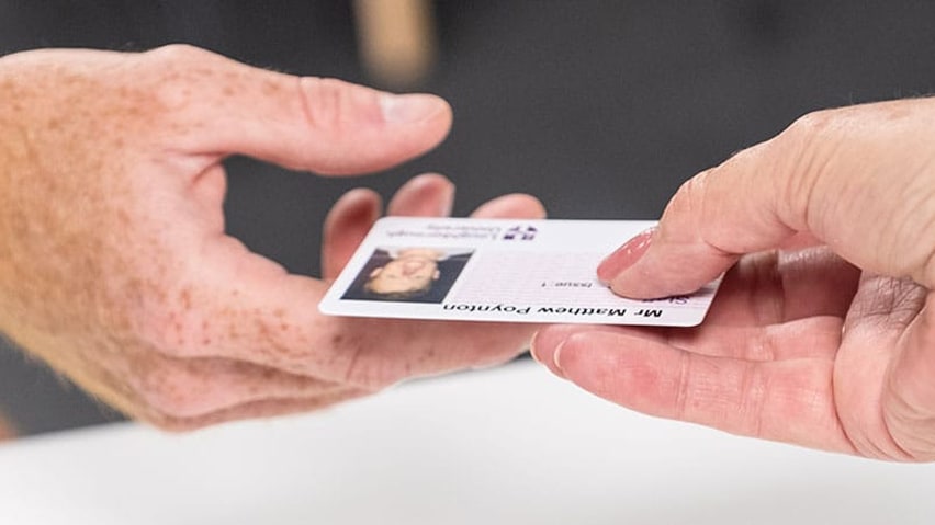 University ID card being passed from one hand to another