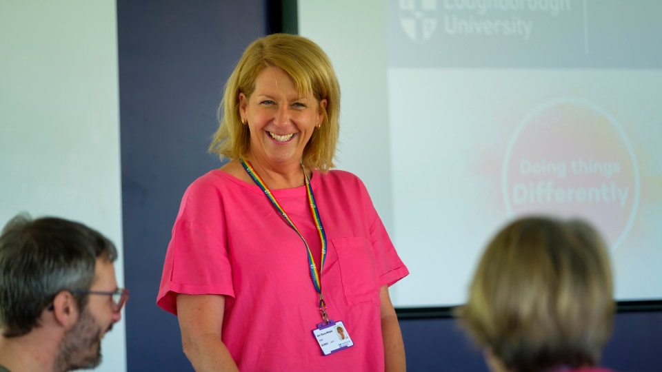 Member of staff stood smiling in front of colleagues