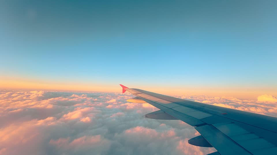 an aeroplane wing with clouds below