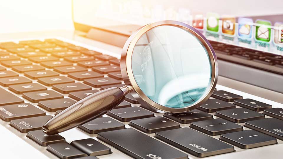 An image of a magnifying glass on top of a laptop keyboard