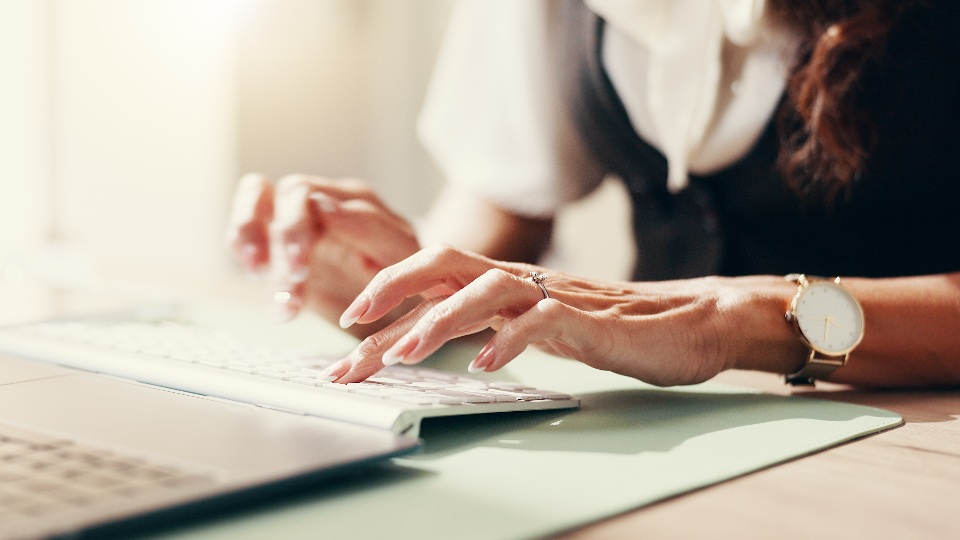 A close up of a person's hands typing on a laptop