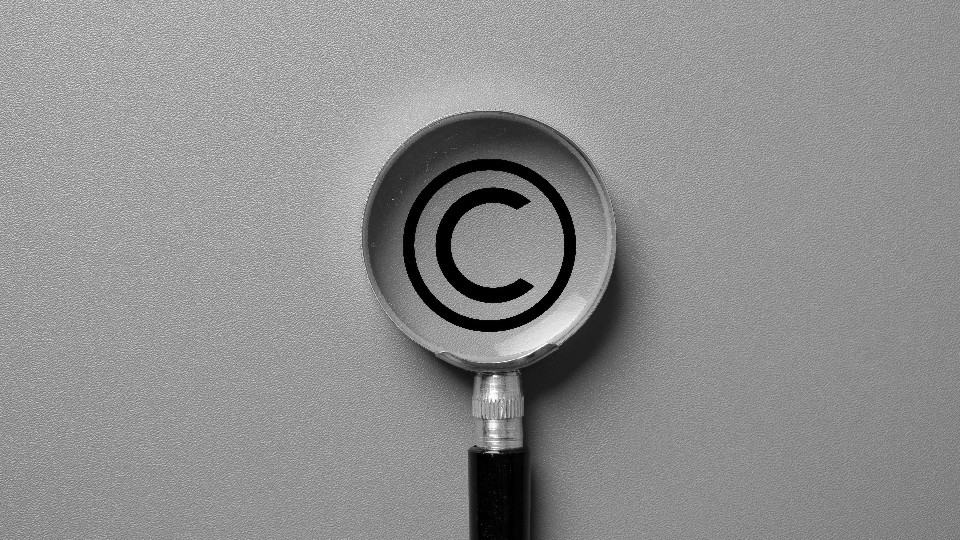The copyright logo on a grey background with a magnifying glass over the logo