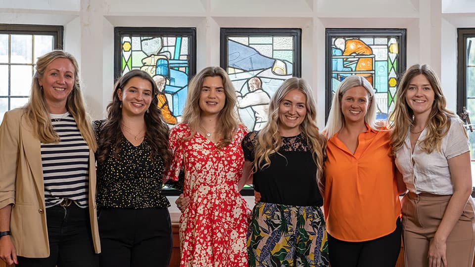 the Philanthropy team standing in a row in front of stained glass windows