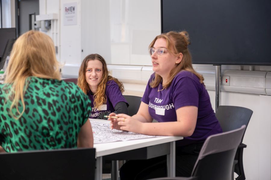 Two students and a staff member sat around a table