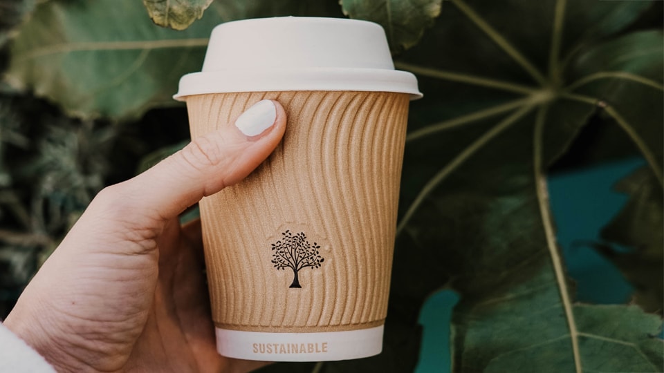 Cardboard cup against leaves