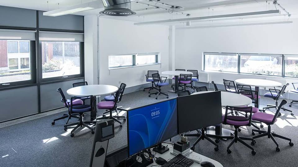 Keith Green Teaching Hub - KTG003 - ground floor flat teaching space with white walls and grey carpets, circular white tables and colourful chairs