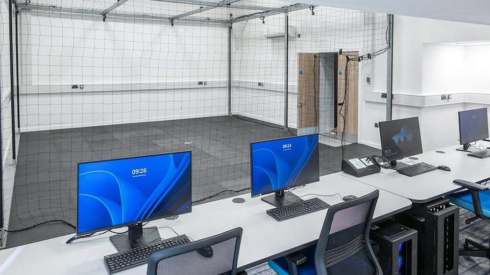 DigiLabs Central - DLC004 Drone Lab - a space for flying drones indoors with mesh separating the drones from a bank of PCs