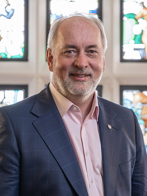 Professor Nick Jennings standing in front of a stained glass window