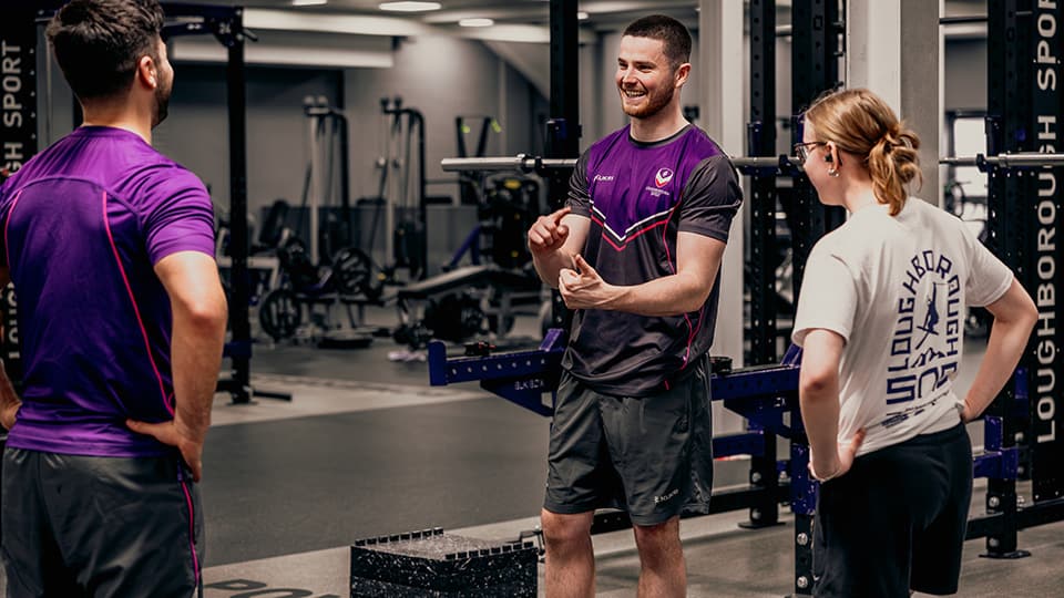 Three people standing chatting in the Powerbase gym surrounded by exercise machines