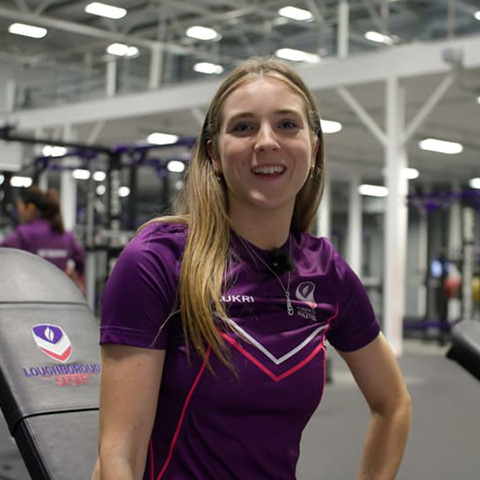 Jess sat on a bench in the gym wearing a Loughborough Sport top