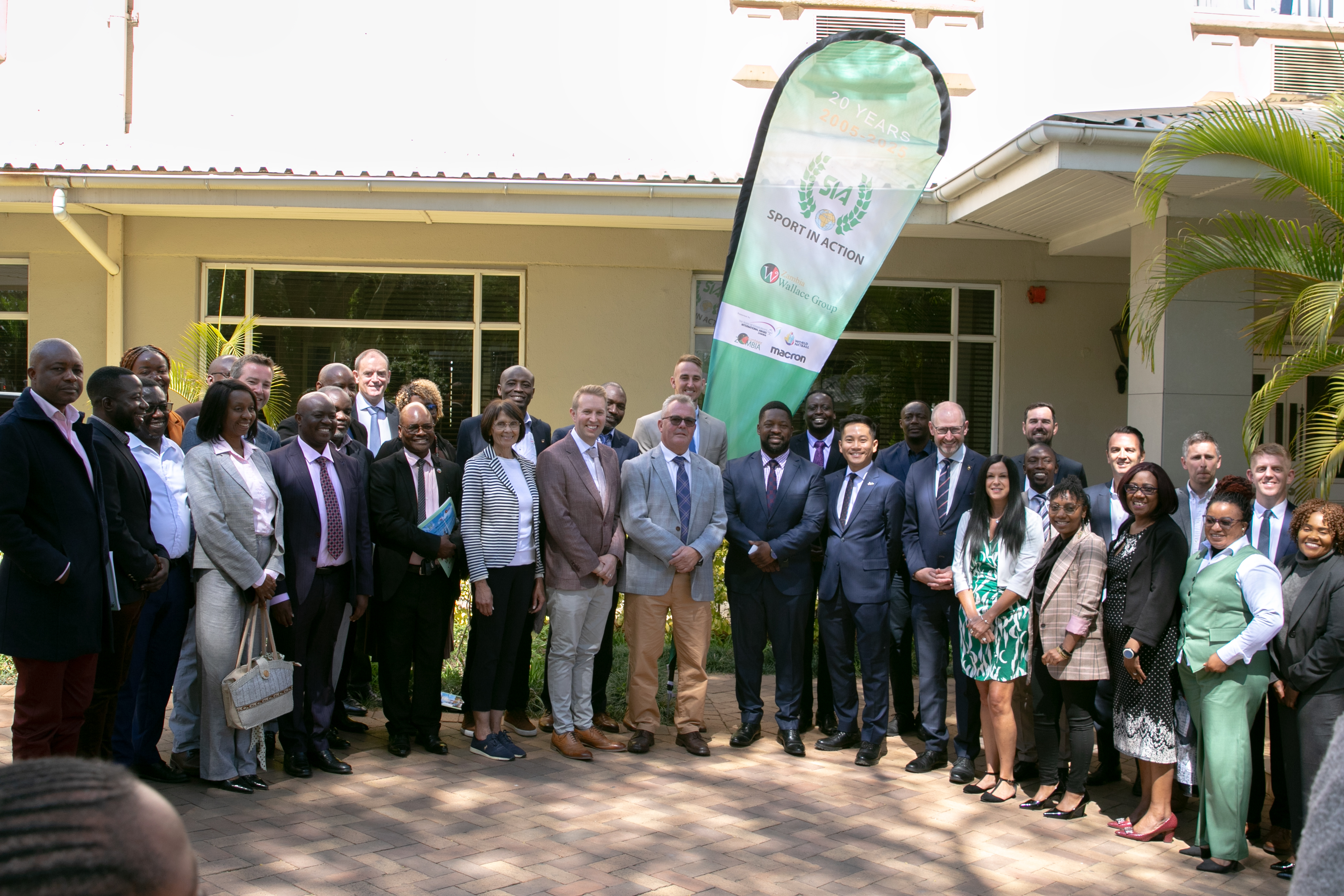 the group of delegates stood in a group outside of a building in zambia