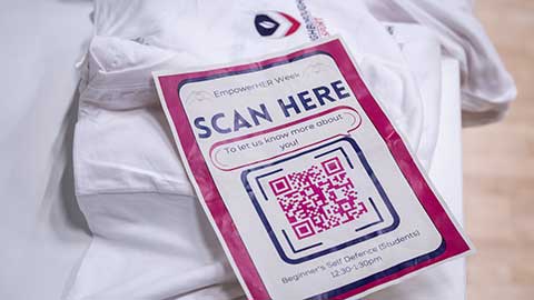 A piece of paper on a table with a QR code and empowerher branding