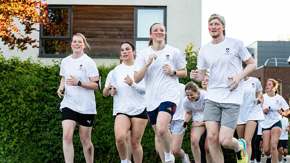 A group of students running and laughing on campus