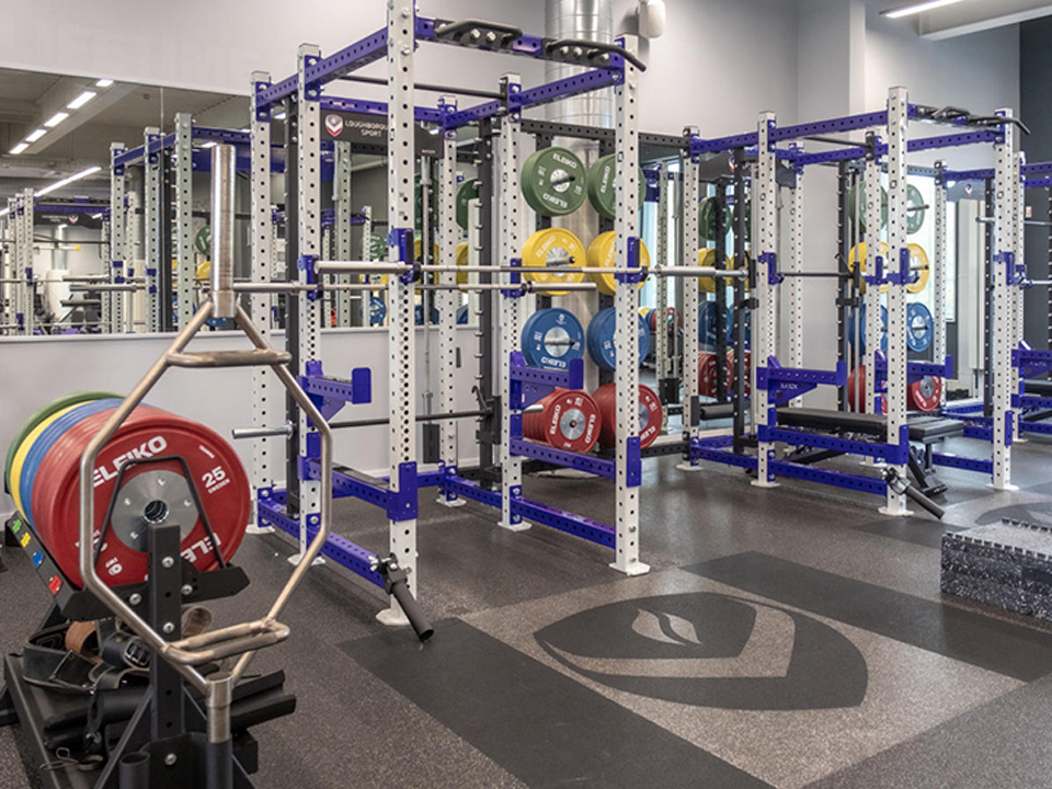 2 squat racks are set up to be used against a mirror wall.