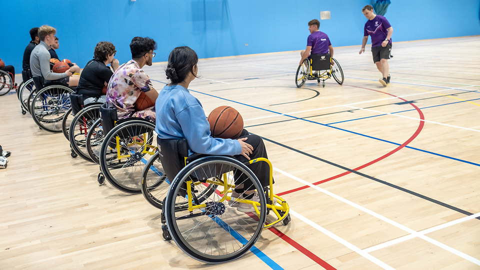 Students are playing Wheelchair Basketball in a sports hall.