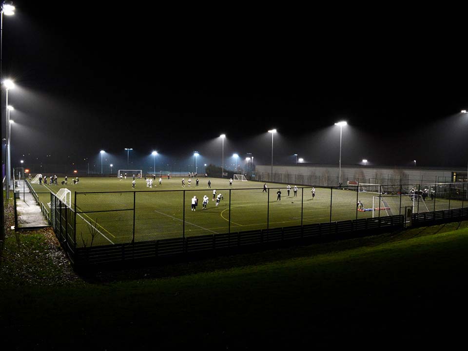 A group of people are training on an artificial pitch.