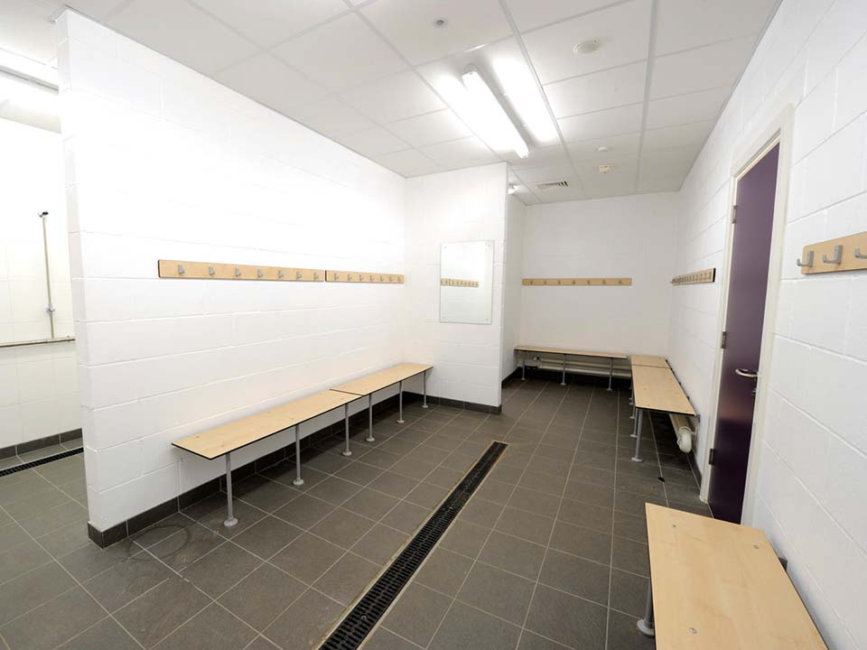 A changing room with showers and hooks.