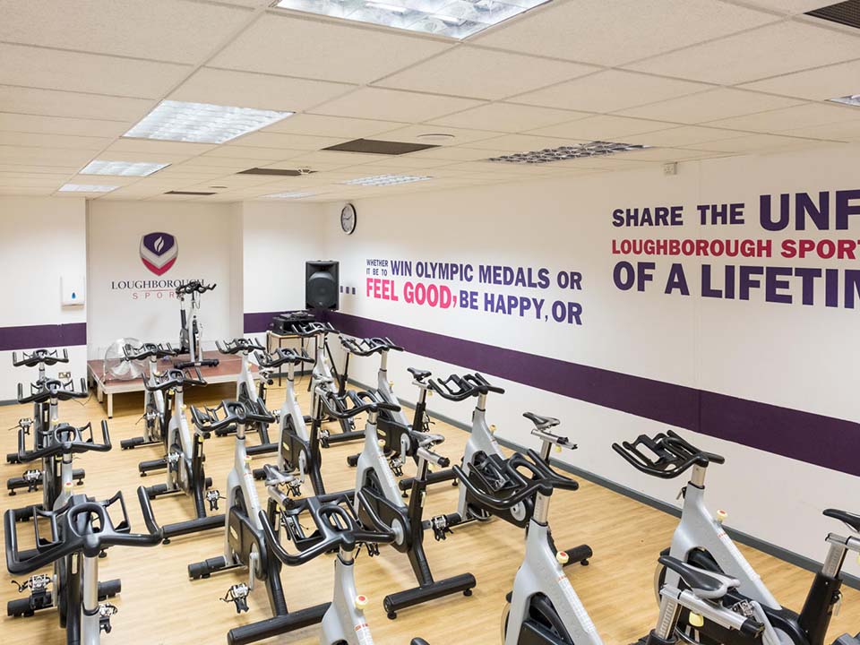 Numerous spin bikes are set up in a studio facing the front bike.