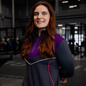Bex is smiling standing side of, wearing a Loughborough Sport quarter zip.