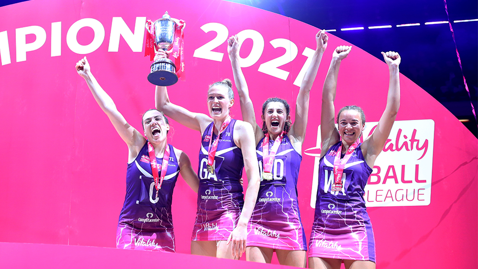 four players celebrating, one holds a trophy
