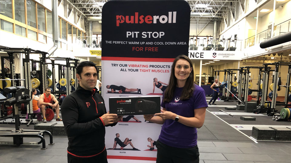 two people standing in the gym in front of a Pulseroll banner