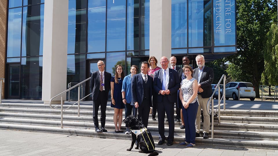 a group of people and an assistance dog on the steps outside a building