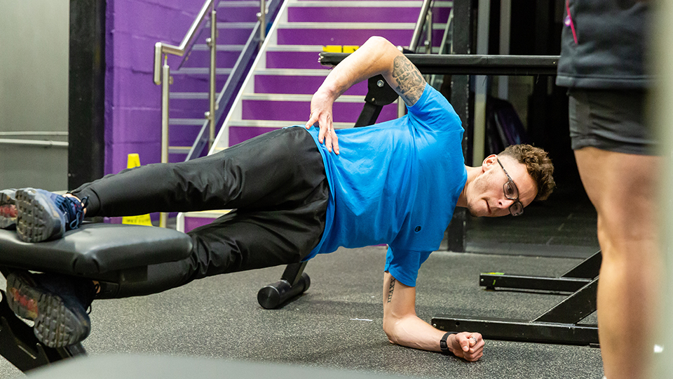 a man holding a side plank in the gym