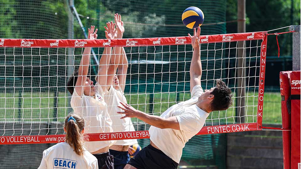 A group of players enjoying a volleyball game on a court, with the net prominently displayed in the middle.