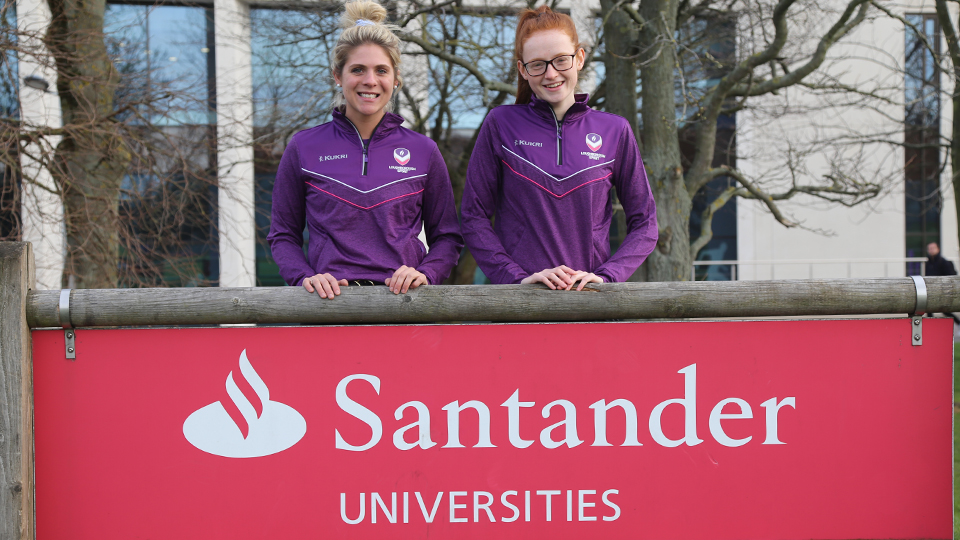 two players standing next to a Santander Universities advertising sign