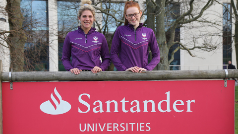 two players standing next to a Santander Universities advertising sign