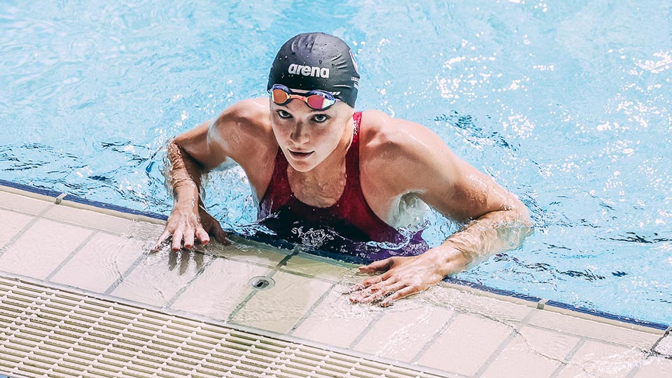 A female swimmer about to get out of the pool