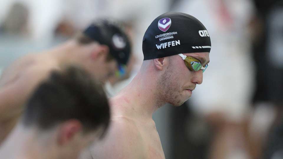A side shot of athlete, Daniel Wiffen wearing goggles and a Loughborough Swimming swim cap