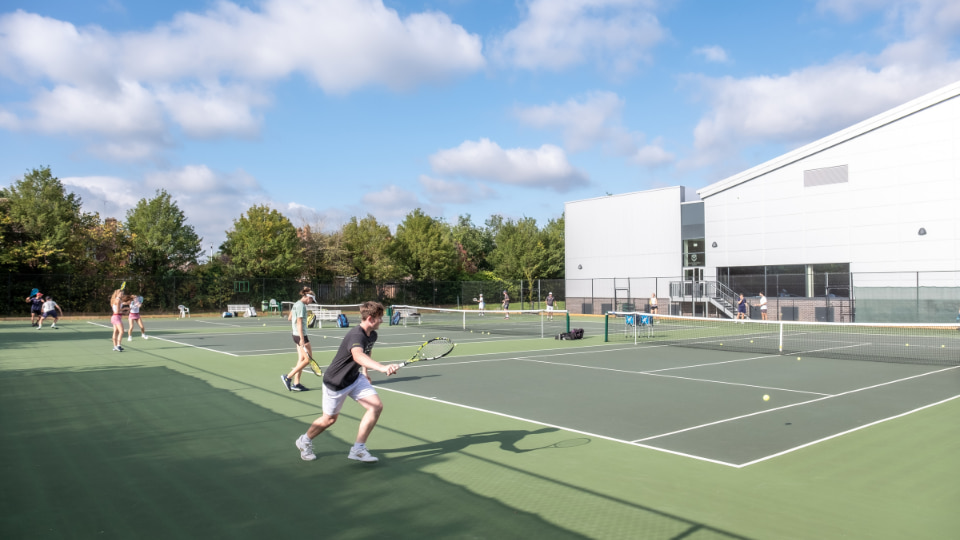 Tennis players playing on an outdoor tennis court under a blue sky