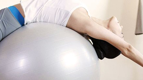 a woman stretching over a fitness ball