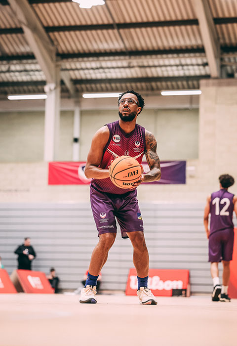 Alumni, Elijah Bailey, holding a basketball on court wearing Loughborough Basketball kit