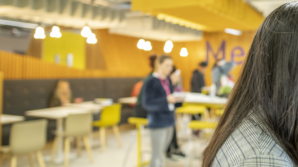 a woman in the foreground and people in the background of the cafe
