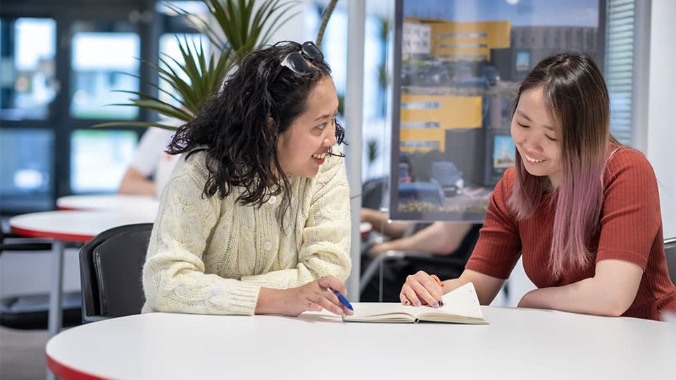 two people sitting at a table in the library and interacting