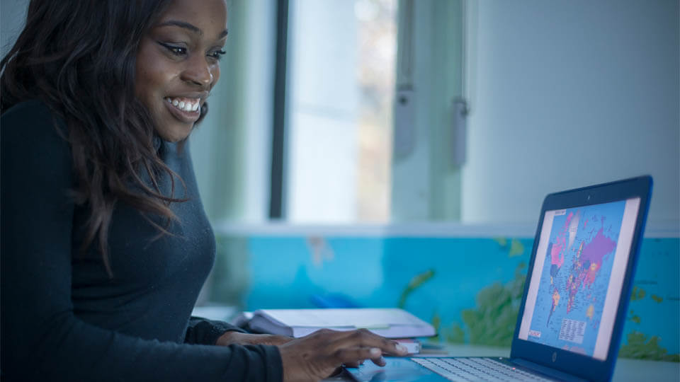 student looking at a world map on a laptop screen