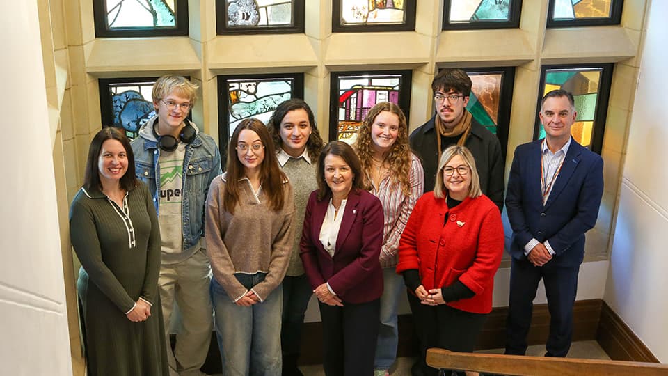 Arts scholars stood in front of a stained glass window