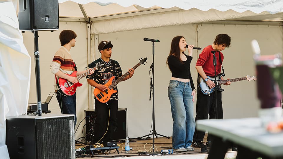 A singer and guitarists on a stage rehearsing