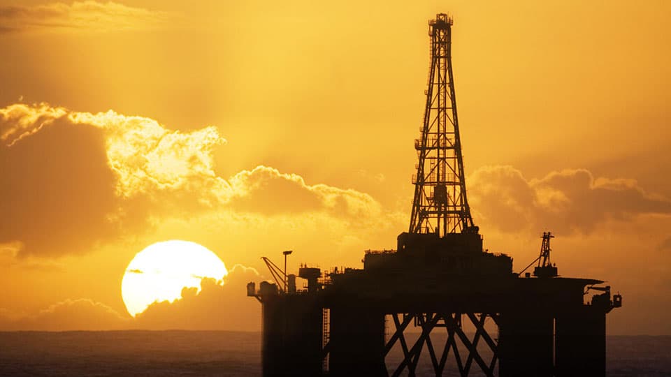 An oil rig with the sun setting behind.
